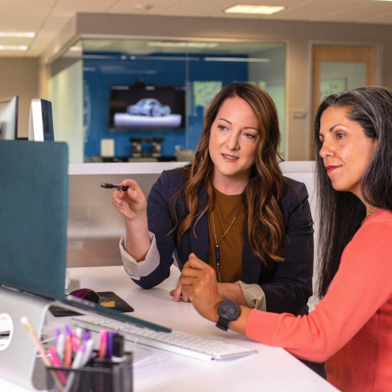 Florida small business owners reviewing available health insurance plan options with an advisor at an office workstation.