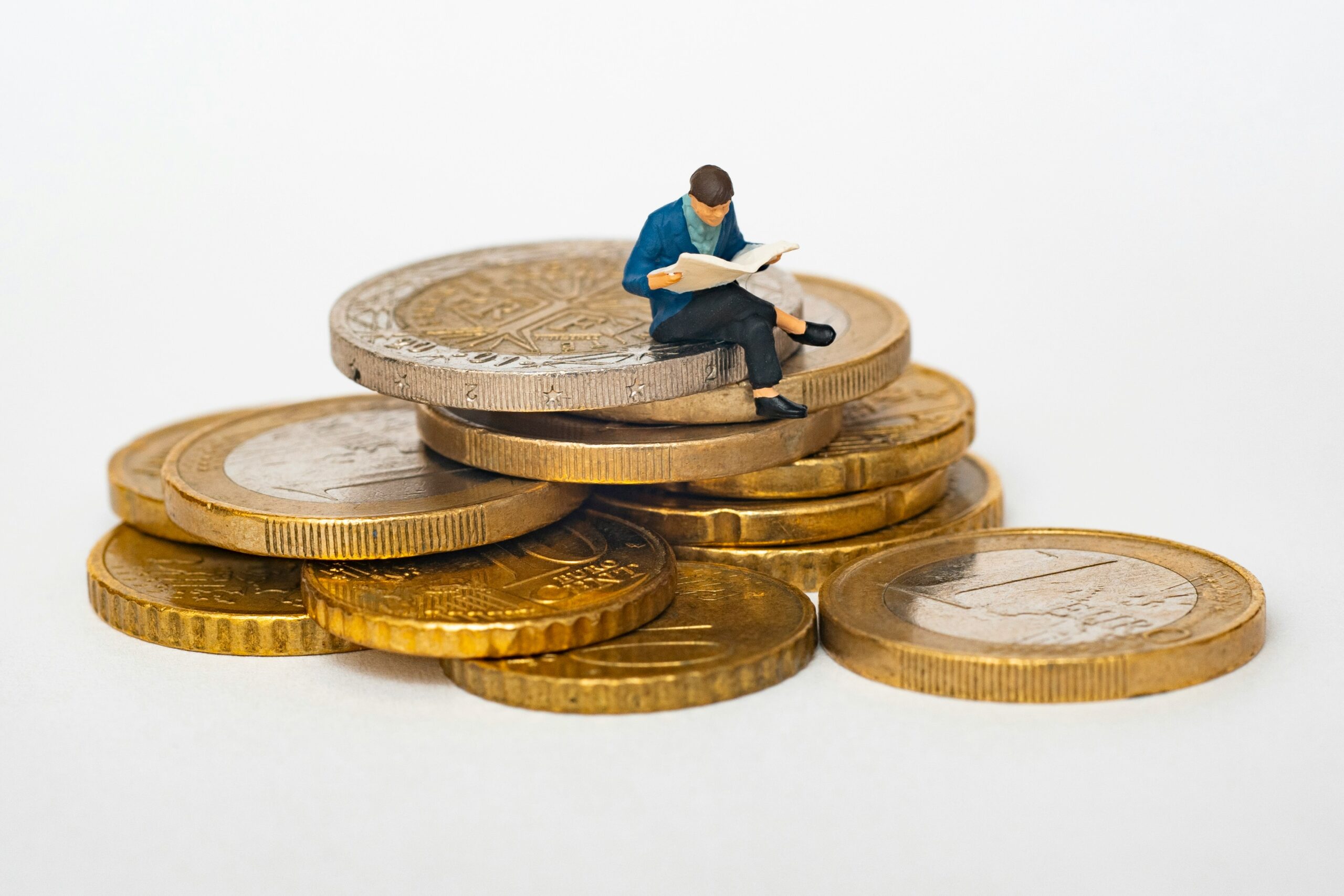 A miniature business figure sitting on stacked coins, representing strategies for small businesses to lower group health insurance costs in Florida.
