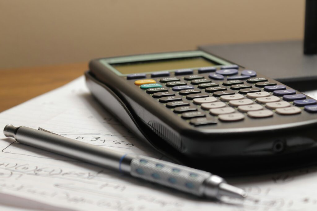 A calculator and notes on a desk,.