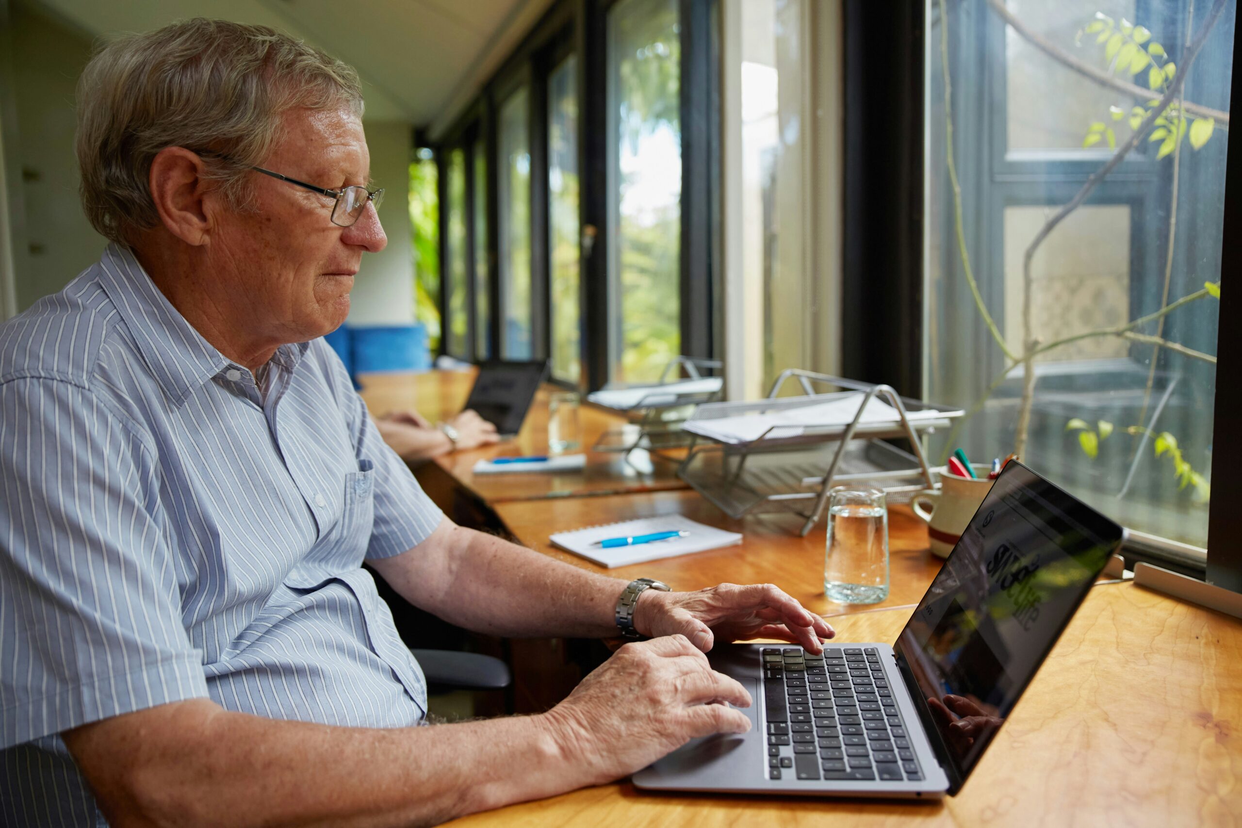 A senior reviewing information on a laptop, representing evaluating costs and benefits of Medicare options in Florida.