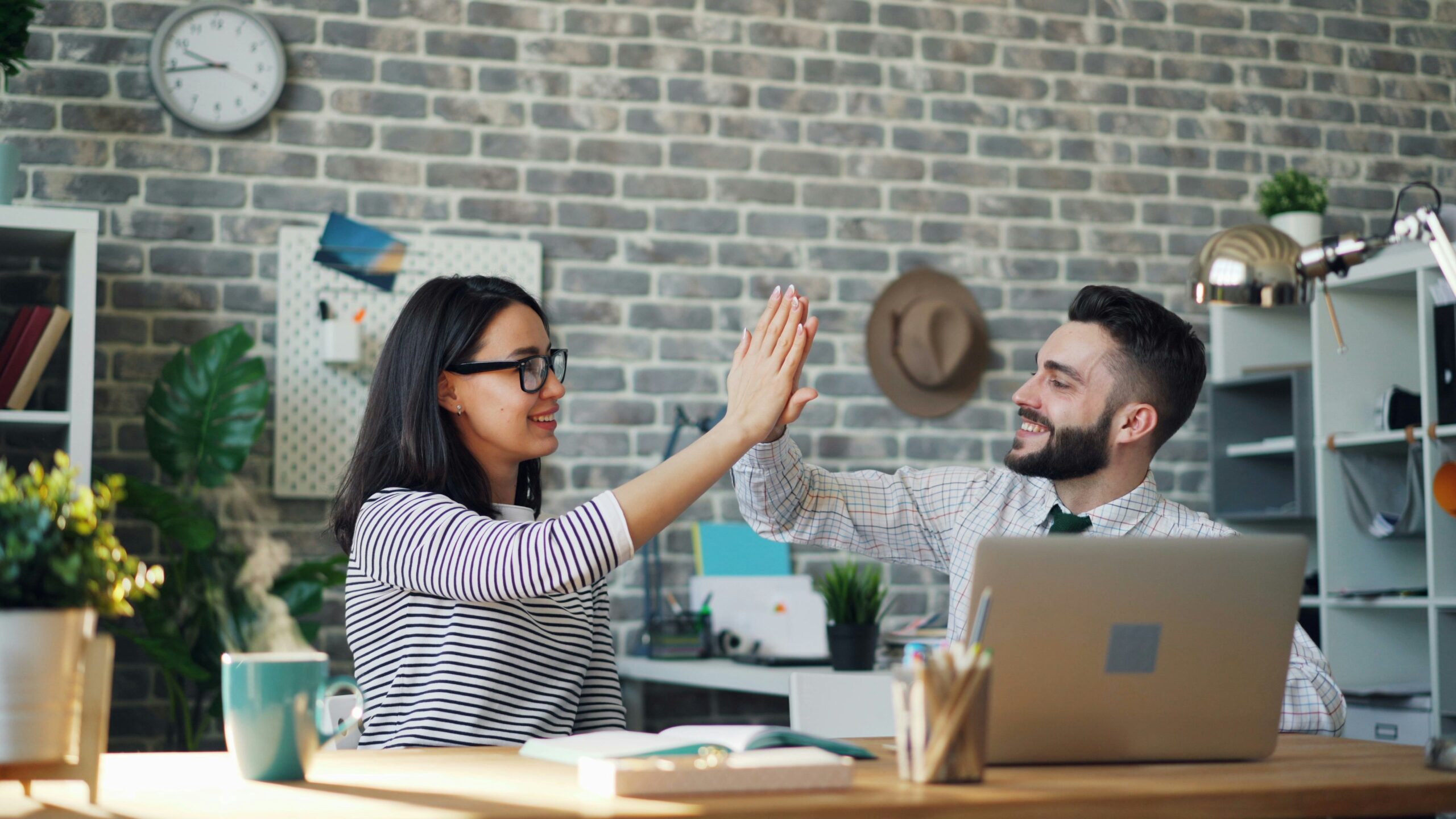 Two coworkers celebrating a successful decision, representing the benefits of choosing group health insurance in Florida.