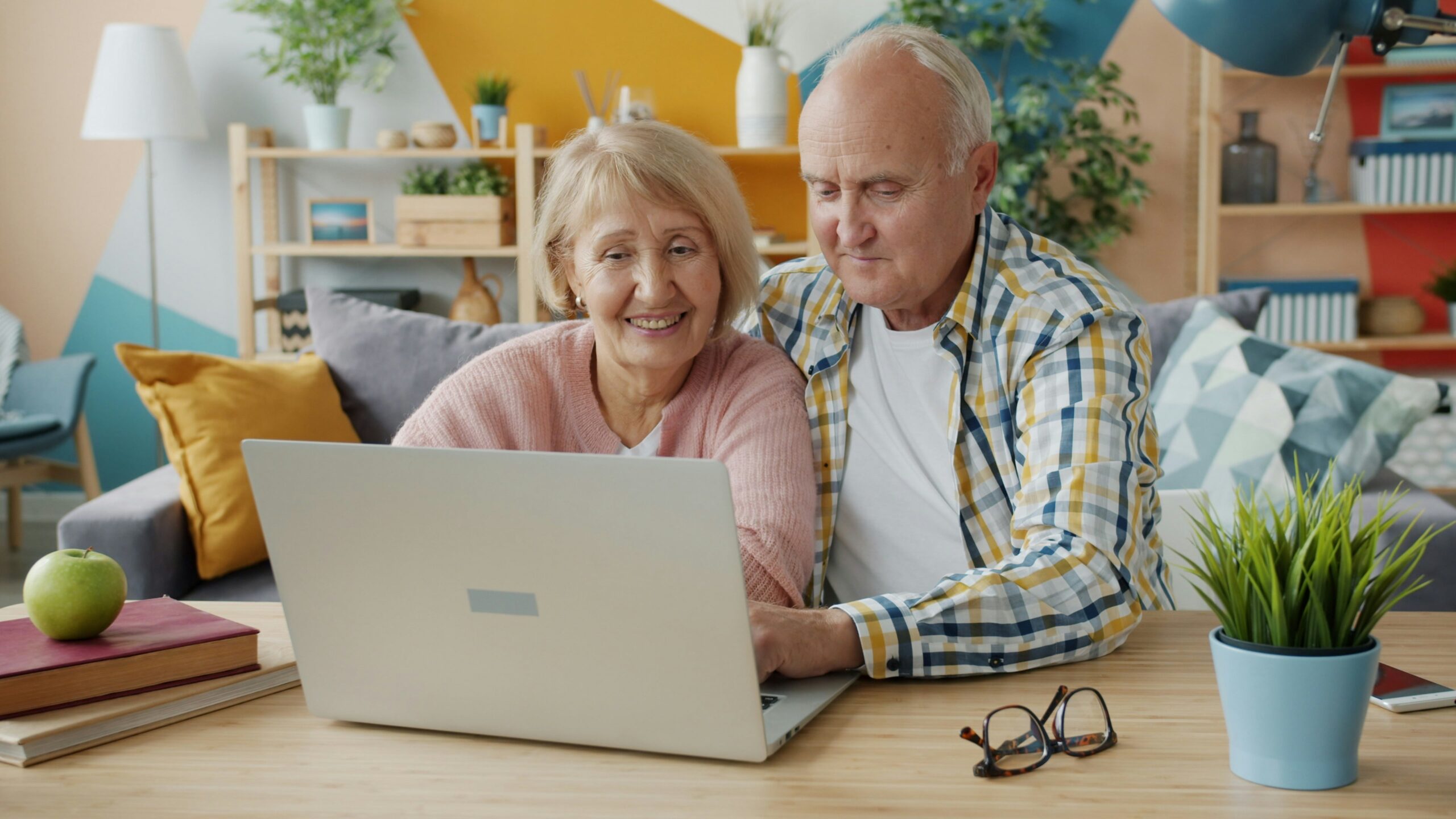 A senior couple reviewing information on a laptop, representing Medicare eligibility and enrollment timing in Florida.