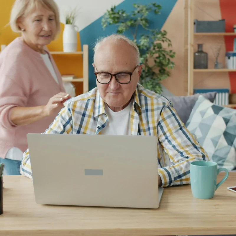A Florida senior reviewing Medicare coverage online, with a spouse offering support at home.