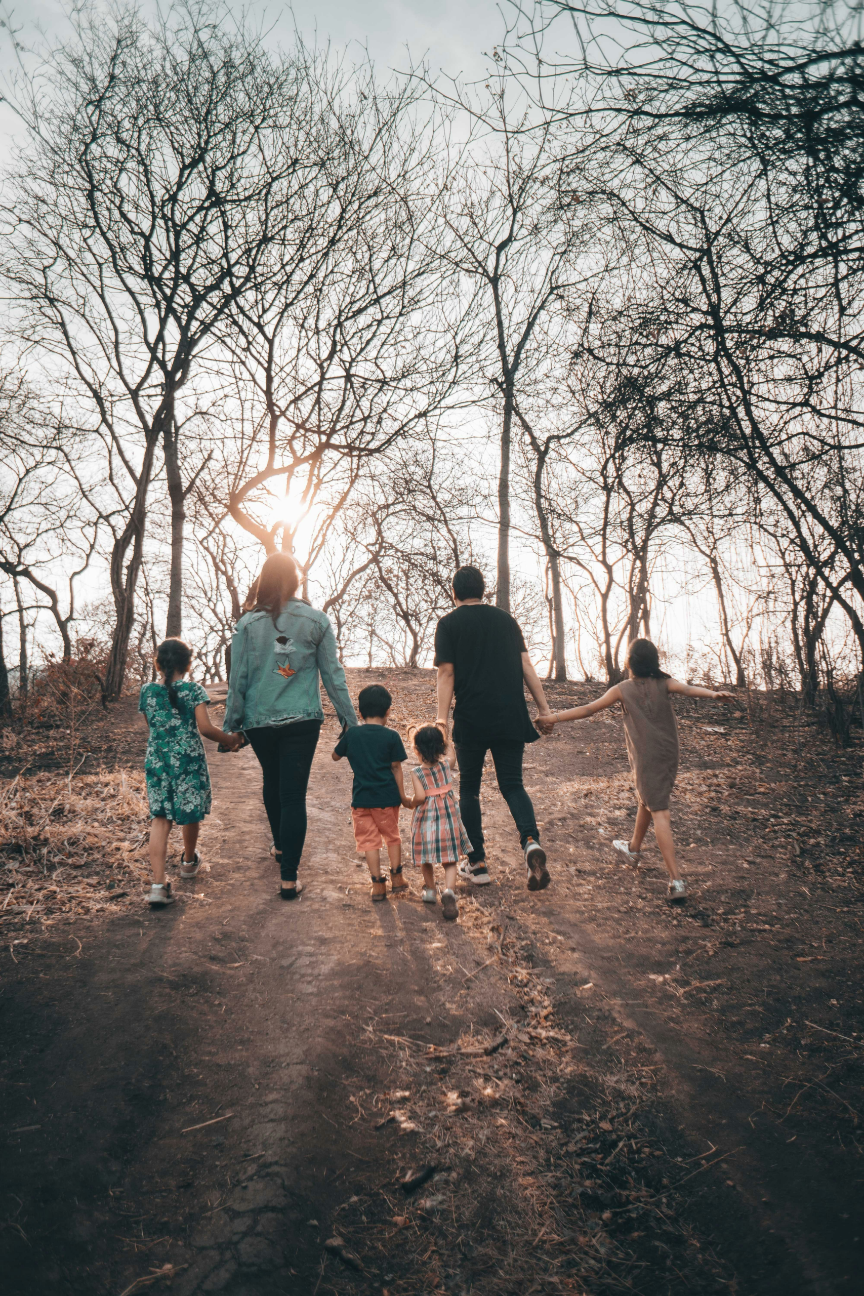 Family walking together on a dirt path through a wooded area, symbolizing the journey to find affordable family health insurance in Florida.