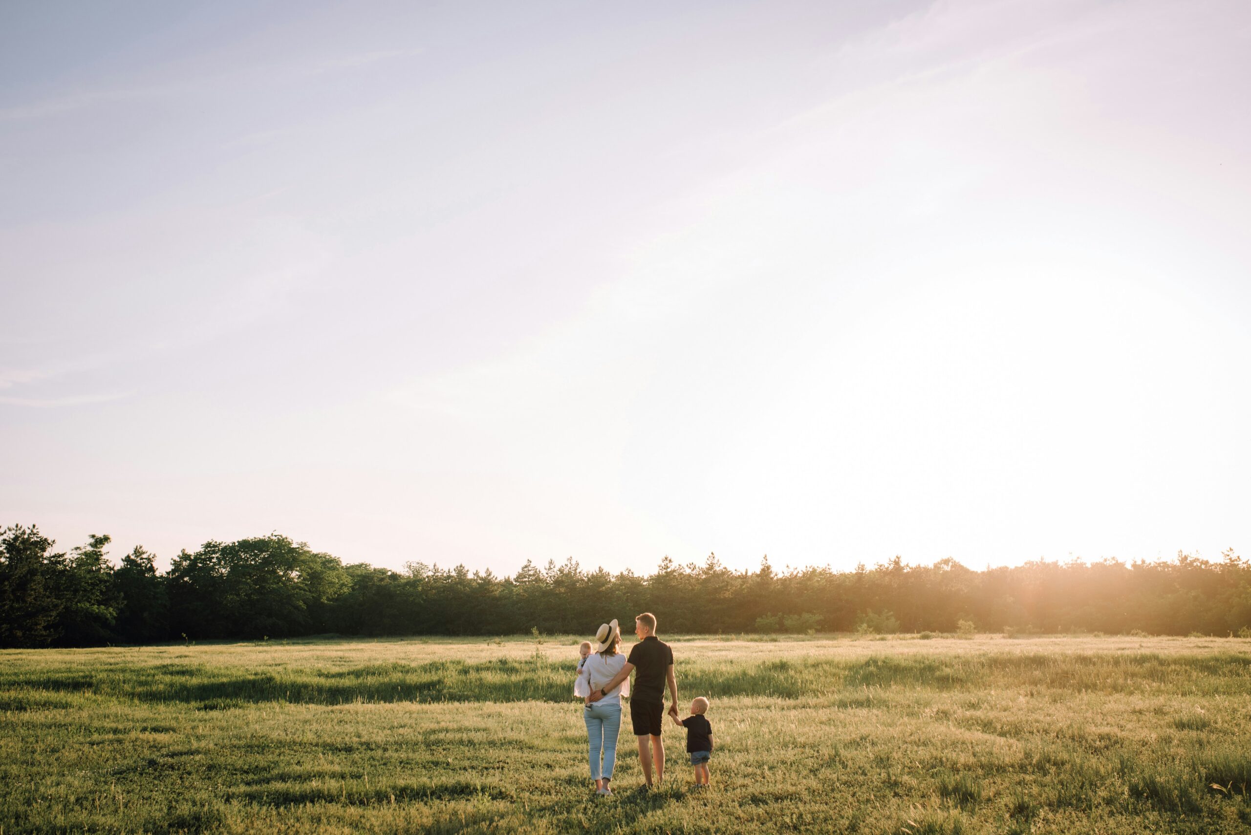 Family walking together in a grassy field during sunset, symbolizing family health insurance options and support in Florida.