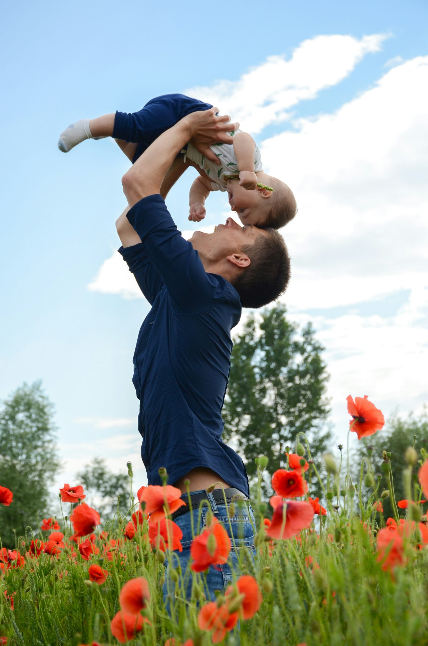 A Florida parent lifting a baby outdoors, symbolizing how age impacts individual and family health insurance needs and coverage decisions.
