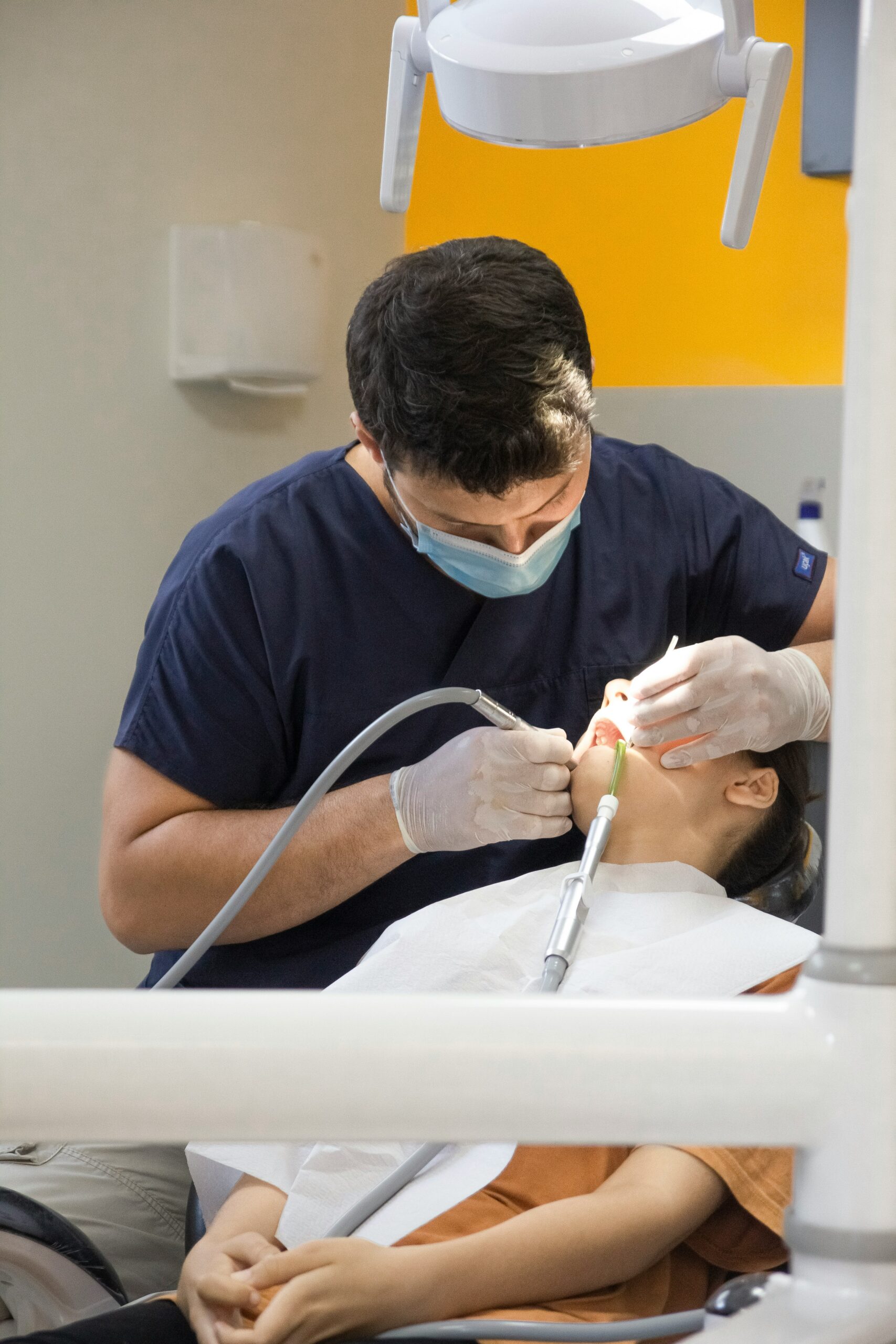 Dentist performing dental treatment on a patient in a clinical setting, highlighting dental care and preventive services relevant to Medicare Advantage plans.