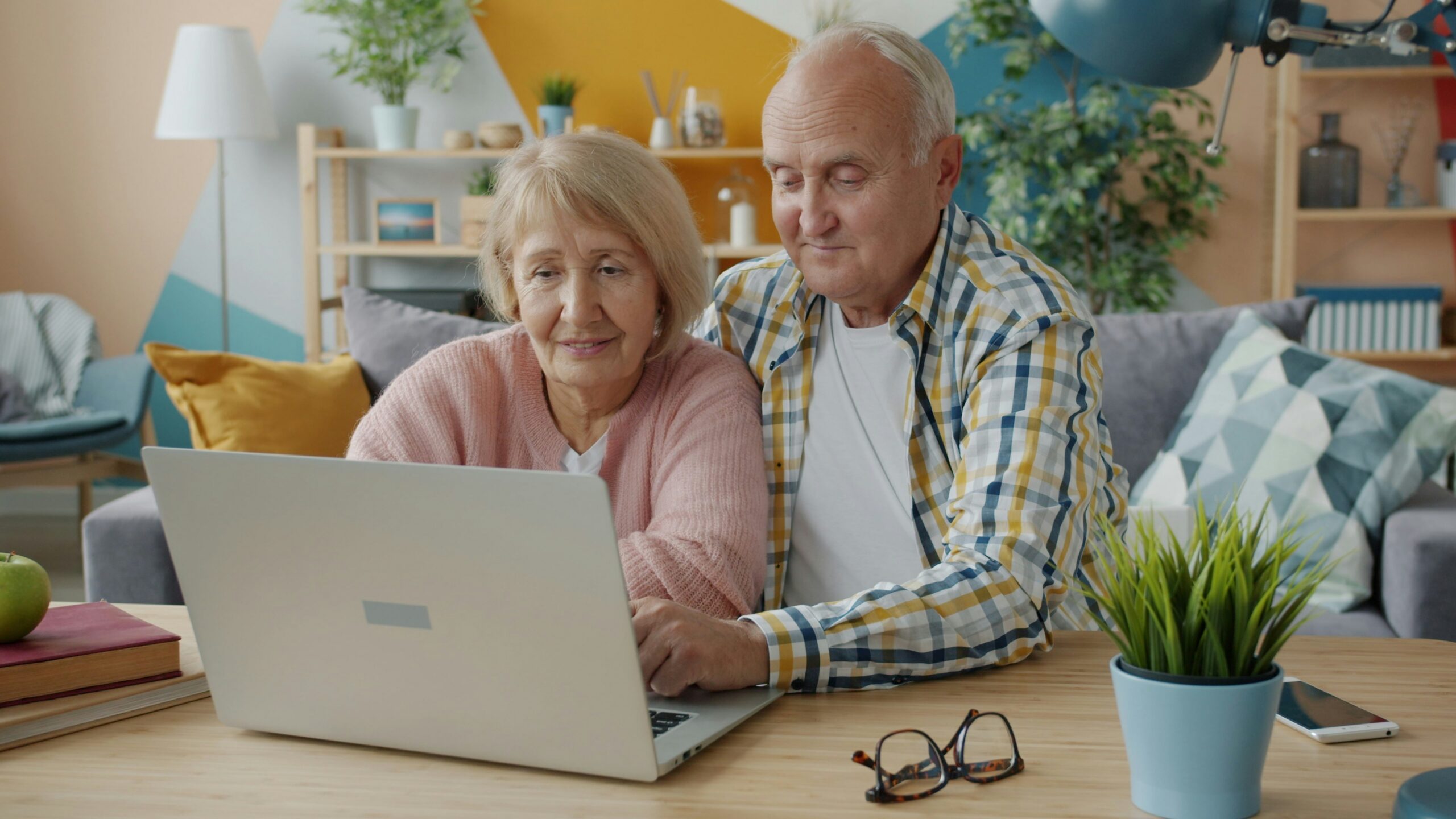 Senior couple reviewing health insurance options on a laptop during a consultation in a cozy living room setting.