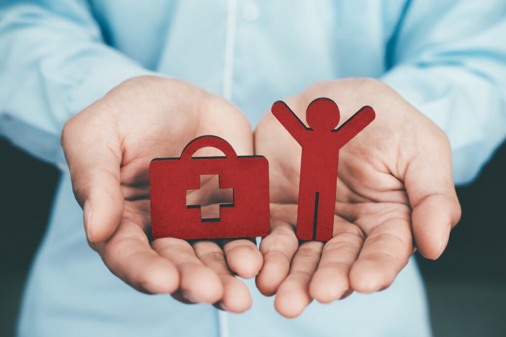 Hands holding healthcare and insurance symbols representing the financial benefits and protection offered through group health coverage.