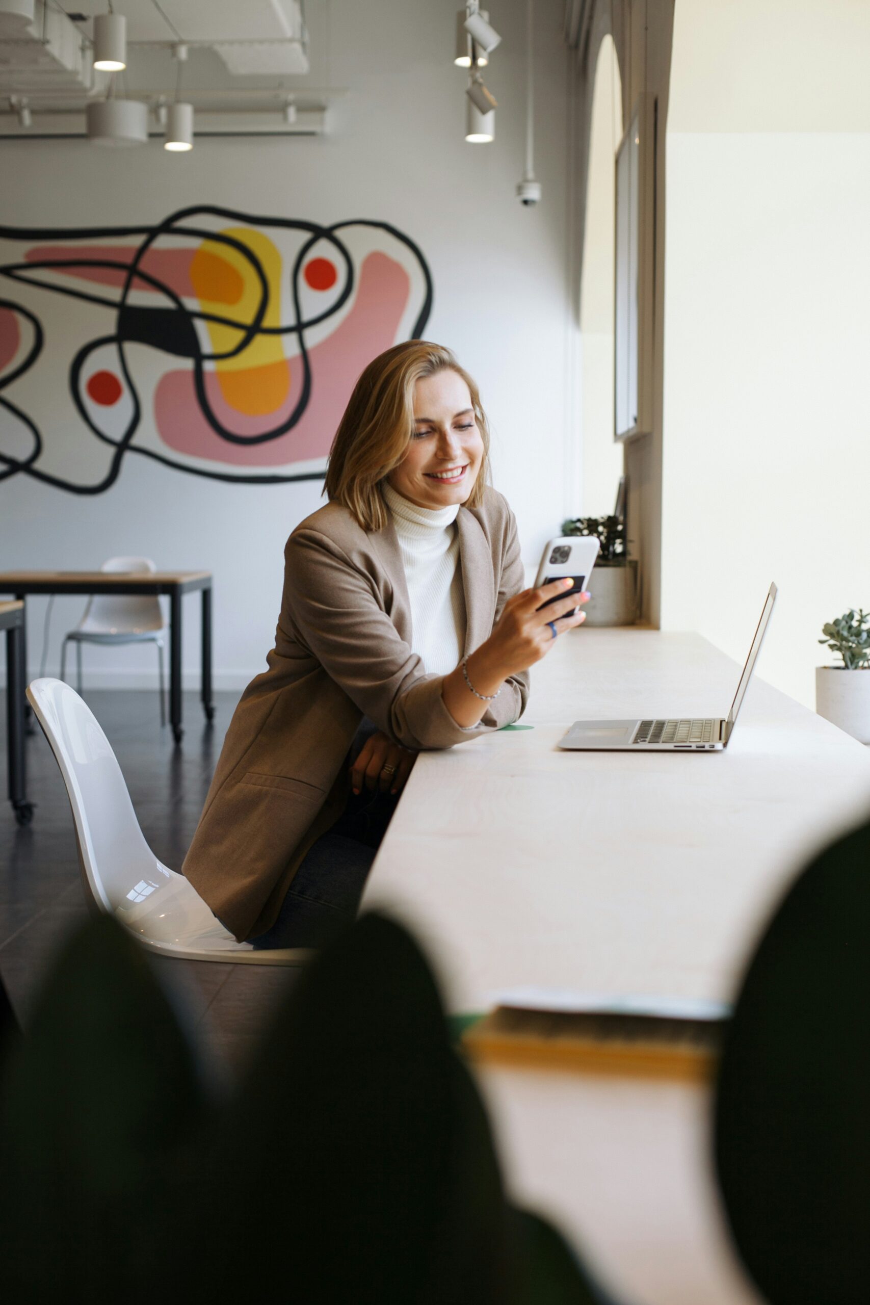 Woman reviewing health insurance eligibility information while using a phone and laptop. | ProCare Consulting Woman reviewing health insurance eligibility information while using a phone and laptop.