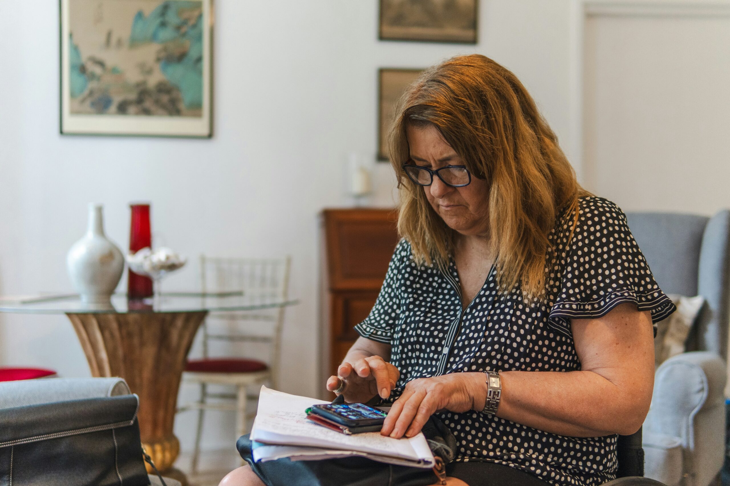 photo 1756312177954 d31ffd5fd68ajpeg | ProCare Consulting Senior woman using her phone while reviewing Medicare supplemental coverage information at home.