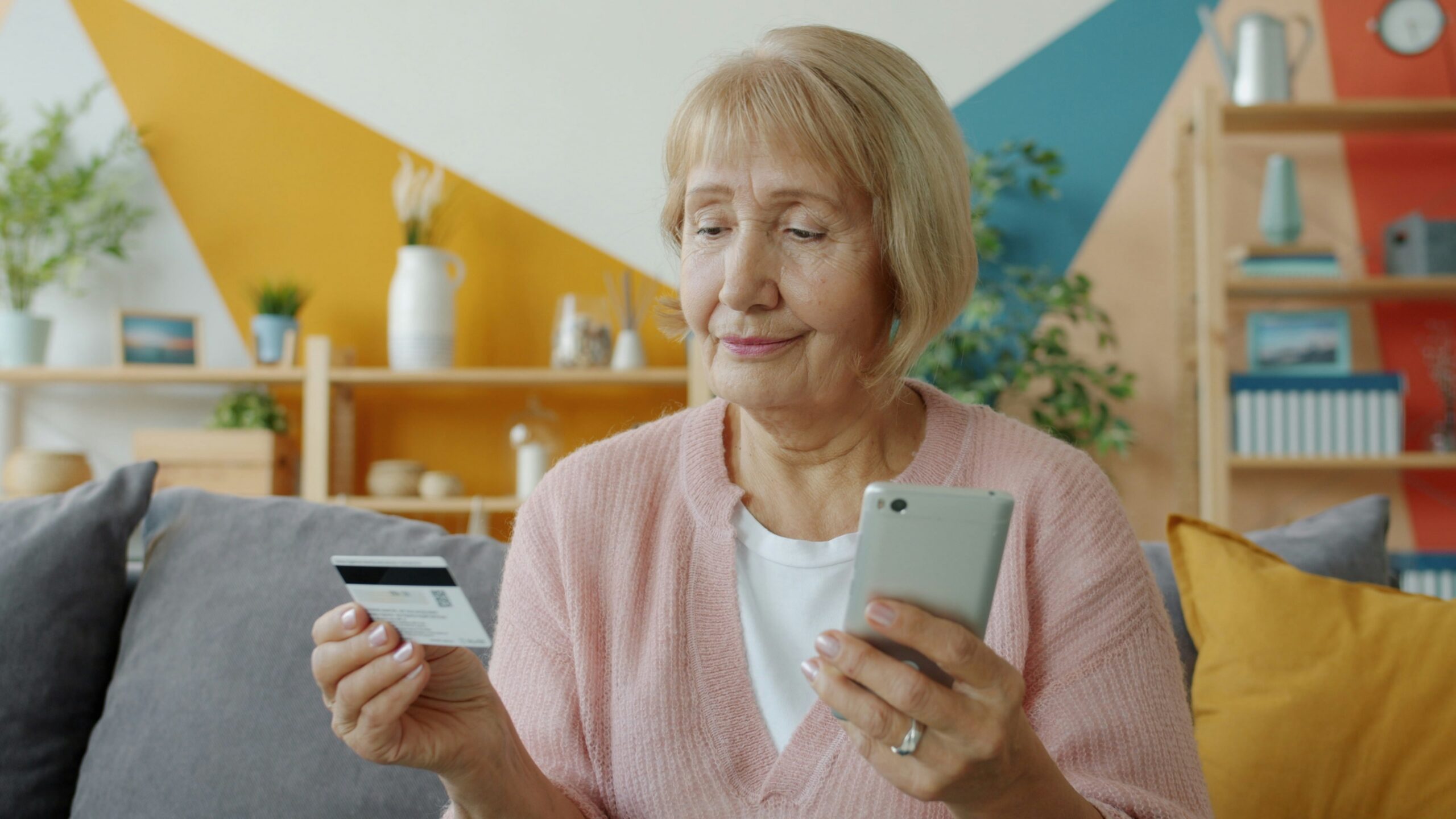 Senior woman using her phone while reviewing Medicare supplemental coverage information at home. | ProCare Consulting Senior woman using her phone while reviewing Medicare supplemental coverage information at home.