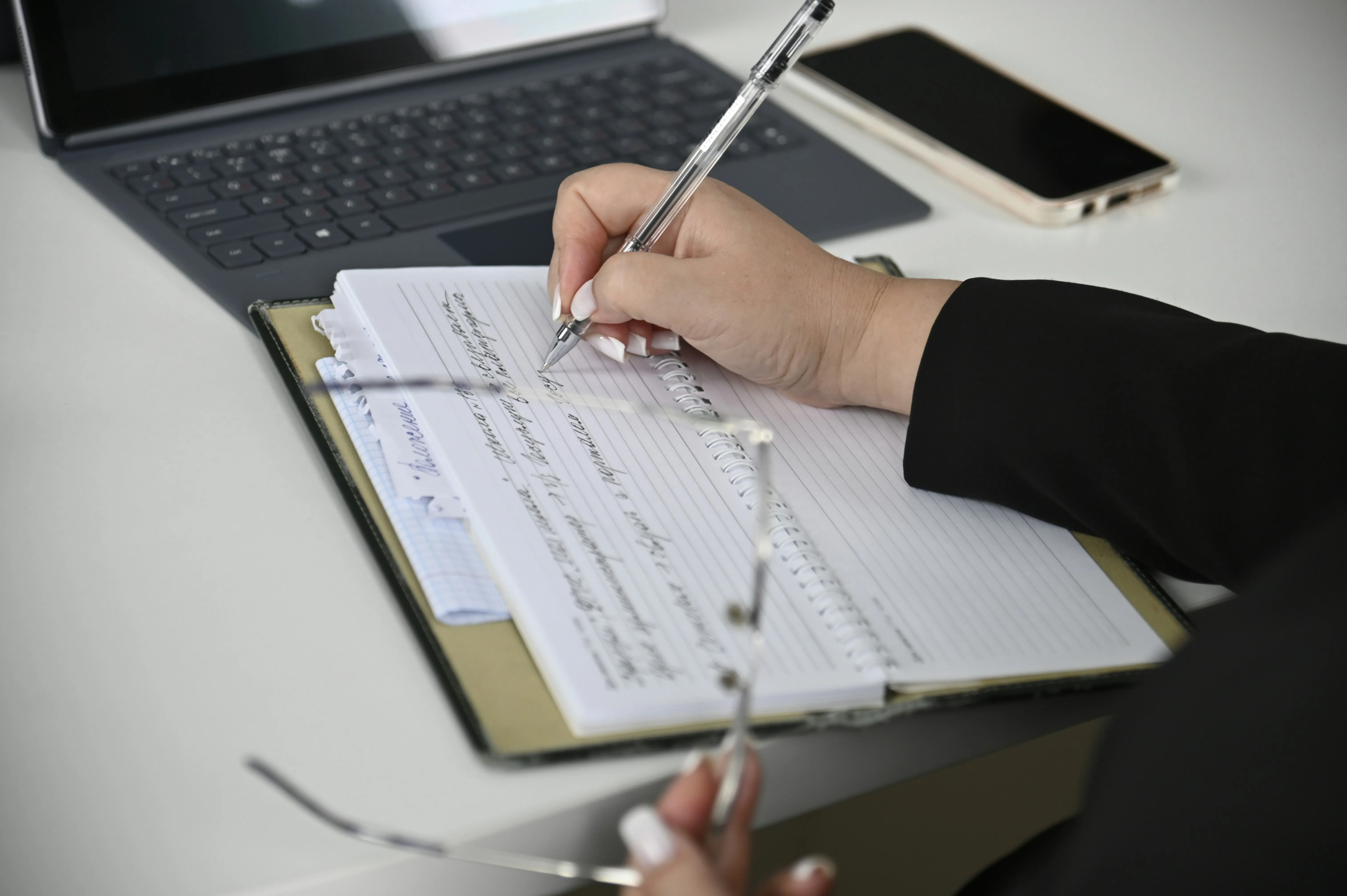 Hand completing a form beside a laptop | ProCare Consulting Hand completing a form beside a laptop
