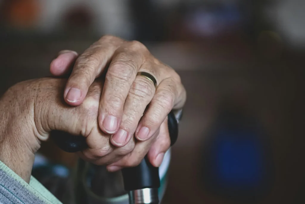 Older adult resting hands on a walking cane