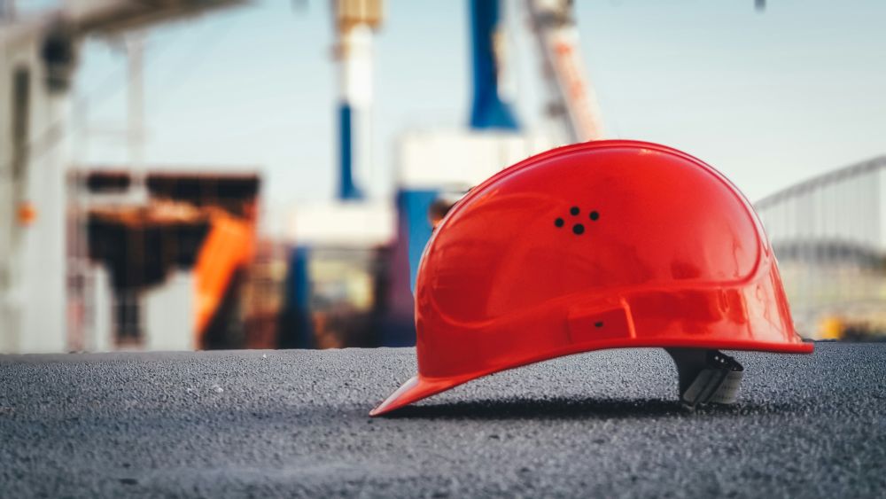 Red safety hard hat at a construction site representing electrical contractor employees and workplace benefits